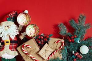 Fir branch, gift box and two cups of cocoa with marshmallows on red background photo