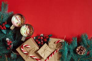 Fir branch, gift box and two cups of cocoa with marshmallows on red background photo