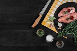Raw chicken fillet with cooking ingredients on black slate table. Food background. Top view, copy space. photo