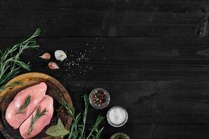 Raw chicken breast fillets on wooden cutting board with herbs and spices. Top view with copy space photo