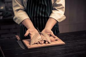 cocinero corte el pescado en un tablero foto