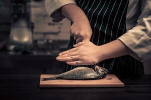 Chef cutting the fish on a board photo