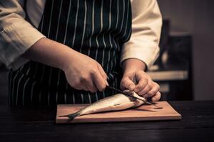 cocinero corte el pescado en un tablero foto