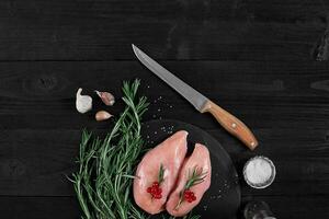 Cooking chicken breasts. On the table are spices - rosemary, red and black pepper. Concept - healthy food. photo