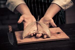Chef cutting the fish on a board photo