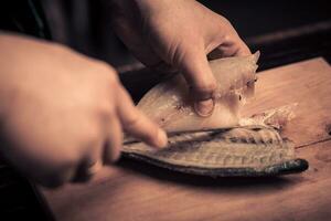 cocinero corte el pescado en un tablero foto