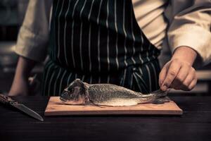 cocinero corte el pescado en un tablero foto