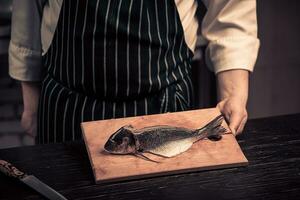 cocinero corte el pescado en un tablero foto