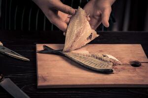 cocinero corte el pescado en un tablero foto