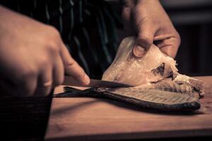 cocinero corte el pescado en un tablero foto