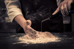 The chef makes dough for pasta on a wooden table photo