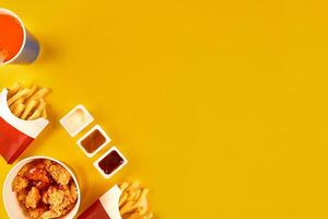 Fast food dish on yellow background. Fast food set fried chicken and french fries. Take away fast food. photo