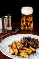 Pork knuckle with potatoes, cabbage and beer on a wooden table. Black background. photo