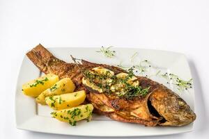 Grilled carp fish with rosemary potatoes and lemon, close up photo