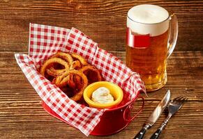 frito empanizado cebolla anillos con salsa y vaso cerveza en de madera mesa foto