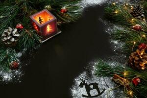 Christmas, christmas tree, candle, snow, cones and cinnamon sticks on black background photo