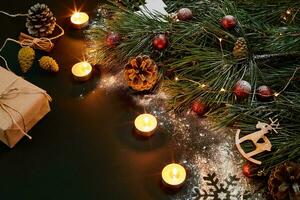 Christmas. Xmas toys, burning candles and spruce branch on black background top view. Space for text photo