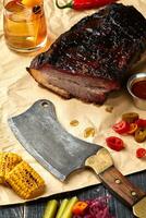 Fresh Brisket BBQ beef sliced for serving against a kraft paper background with sauce, hot peppers and corn. photo