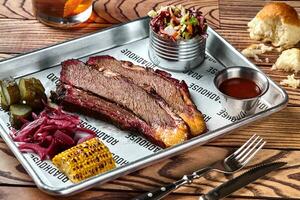 Smoked barbecue beef brisket with sauce, corn, marinated cucumber and onions photo