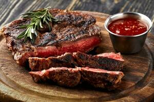 Juicy steak medium rare beef with spices on wooden board on table photo