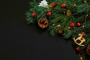 Christmas. Xmas toys and spruce branch on black background top view. Space for text photo