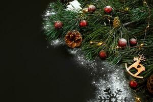 Christmas. Xmas toys and spruce branch on black background top view. Space for text photo