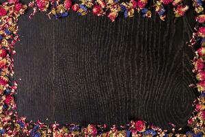 Pile of pink dried roses on black wooden background as border. photo