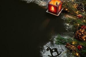 Christmas, christmas tree, candle, snow, cones and cinnamon sticks on black background photo