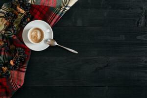 White cup of the coffee and vintage scarf on black wooden background photo