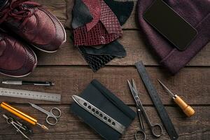 Leather craft or leather working. Leather working tools and cut out pieces of leather on work desk . photo