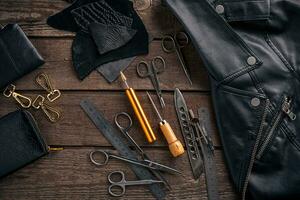 Leather craft or leather working. Leather working tools and cut out pieces of leather on work desk . photo