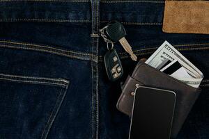 Money, Debit card and Credit card are in pocket of blue jean, Car keys, Smart. Top view photo