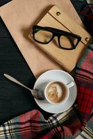 Above view of Smart phone with notebook and cup of latte coffee on black wooden background. photo