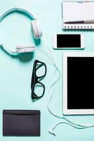 Working place with tablet, smartphone and glasses on a turquoise background photo