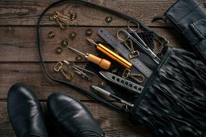 Leather craft or leather working. Leather working tools and cut out pieces of leather on work desk . photo