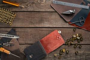 Leather craft or leather working. Leather working tools and cut out pieces of leather on work desk . photo