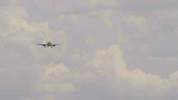 Slow motion, passenger plane approaching for landing. Aircraft flies, front view. Airliner with unrecognizable green livery descending. Panoramic view of airplane in sky. Flight arrival video