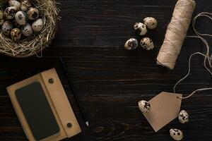 quail eggs in nest, notebook and thread on a black background photo