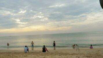 PHUKET, THAILAND FEBRUARY 26, 2023 Airplane over a crowded beach. Tourists take photos in front of a flying airplane. The concept of travel video