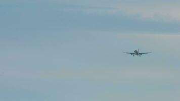 Long shot of commercial jet approaching for landing. Passenger airplane flies, front view. Tourism and aviation concept video