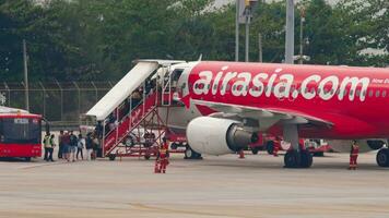PHUKET, THAILAND FEBRUARY 27, 2023 AirAsia jet airplane in Phuket Airport. People board an airplane. Airplane on the airfield, stairway. Travel concept video