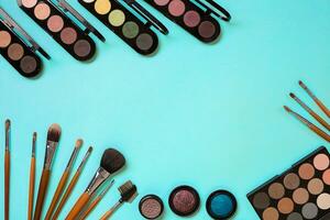 Make up essentials. Set of professional make up brushes, creams and shadows in jars on blue background. photo