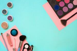 Make up essentials. Set of professional make up brushes, creams and shadows in jars on blue background. photo