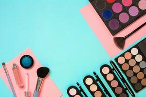 Make up essentials. Set of professional make up brushes, creams and shadows in jars on blue background. photo
