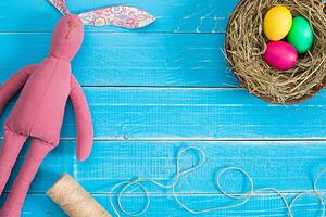 Easter eggs in nest and rabbit on blue rustic wooden planks photo