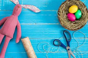 Colorful easter egg in nest on blue wood board. photo