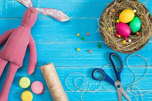 Easter eggs in nest and rabbit on blue rustic wooden planks photo