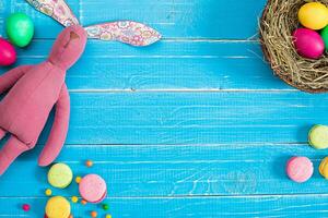 Colorful easter egg in nest on blue wood board. photo