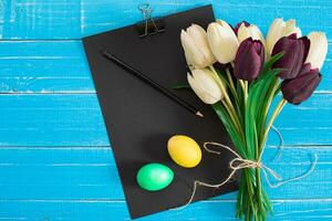 Easter eggs and tulips on blue wooden planks photo