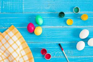 Colorful easter eggs, brush and paint on wooden board background with space. photo